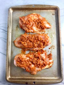 Sun Dried Tomato Chicken breasts raw on a pan. It's slightly sweet, slightly tart and tangy, and hugely delicious! When Sun dried tomatoes are rehydrated and blended, they turn into a thick and lucious sauce that coats the chicken keeping it moist and juicy when it simply bakes in the oven. It's a perfect easy weeknight dinner that you can prepare ahead and cook quickly! #chicken #chickenrecipes #easydinners #dinnerrecipes