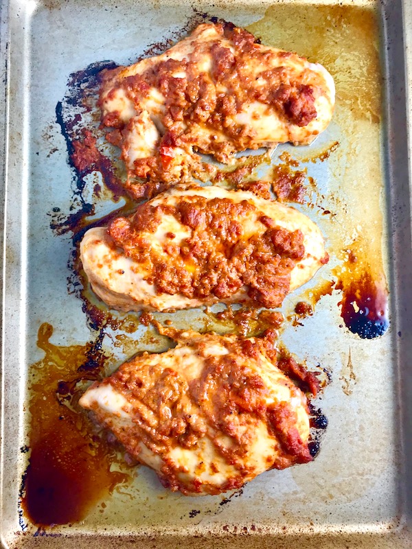 Sun Dried Tomato Chicken breasts cooked on a pan. It's slightly sweet, slightly tart and tangy, and hugely delicious! When Sun dried tomatoes are rehydrated and blended, they turn into a thick and lucious sauce that coats the chicken keeping it moist and juicy when it simply bakes in the oven. It's a perfect easy weeknight dinner that you can prepare ahead and cook quickly! #chicken #chickenrecipes #easydinners #dinnerrecipes