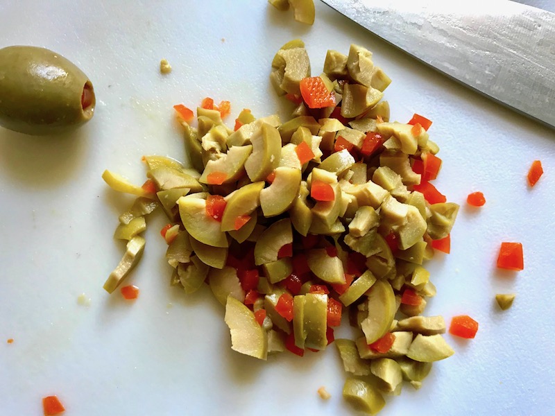 Chopped green olives with pimiento for the Creamy Olive Chicken recipe. This is magnificently thick and creamy and infused with garlic flavor and nuttiness from the Parmesan. The best part; however, is the salty and briny flavor kick from the green olives with a little sweetness from the pimiento. #chicken #chickenrecipes #chickendinner #easydinners #easyrecipes #comfortfood #casserole