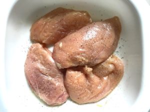 Raw chicken in pan for the Creamy Olive Chicken recipe. This is magnificently thick and creamy and infused with garlic flavor and nuttiness from the Parmesan. The best part; however, is the salty and briny flavor kick from the green olives with a little sweetness from the pimiento. #chicken #chickenrecipes #chickendinner #easydinners #easyrecipes #comfortfood #casserole