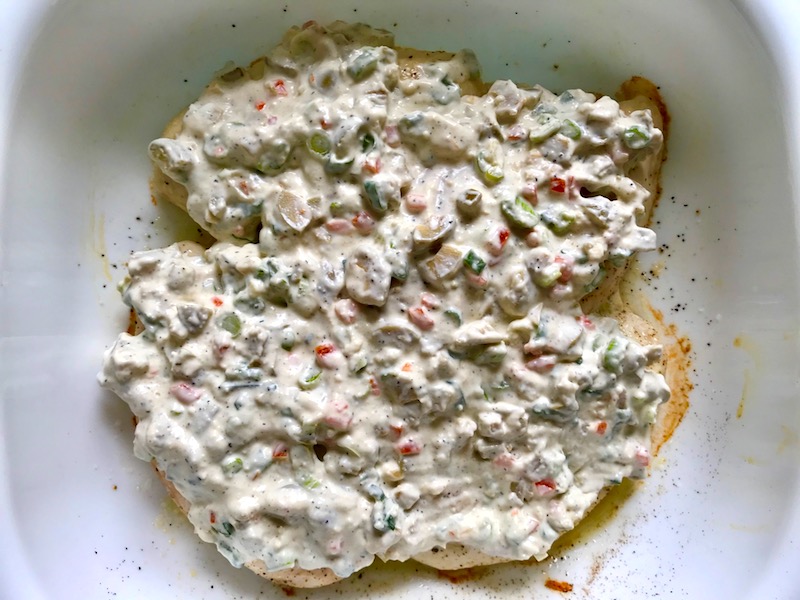 Sauce on Chicken in pan for the Creamy Olive Chicken recipe. This is magnificently thick and creamy and infused with garlic flavor and nuttiness from the Parmesan. The best part; however, is the salty and briny flavor kick from the green olives with a little sweetness from the pimiento. #chicken #chickenrecipes #chickendinner #easydinners #easyrecipes #comfortfood #casserole