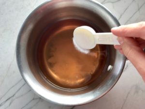 Adding sugar to vinegar for pickling onions for Slow Cooker Pork Tacos with with Pickled Onions, Shredded Cheese, and Cilantro Lime Crema drizzled on top! It's such an easy dinner since the pork cooks in the slow cooker to be perfectly seasoned and fall apart tender. #tacos #easydinner #glutenfree #dinner #mexican #pork