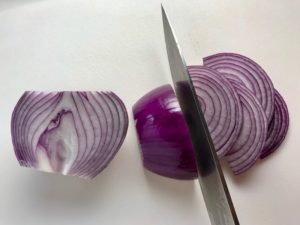 Red Onions being sliced for pickling for Slow Cooker Pork Tacos with with Pickled Onions, Shredded Cheese, and Cilantro Lime Crema drizzled on top! It's such an easy dinner since the pork cooks in the slow cooker to be perfectly seasoned and fall apart tender. #tacos #easydinner #glutenfree #dinner #mexican #pork