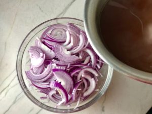 Red Onions in bowl before pickling for Slow Cooker Pork Tacos with with Pickled Onions, Shredded Cheese, and Cilantro Lime Crema drizzled on top! It's such an easy dinner since the pork cooks in the slow cooker to be perfectly seasoned and fall apart tender. #tacos #easydinner #glutenfree #dinner #mexican #pork