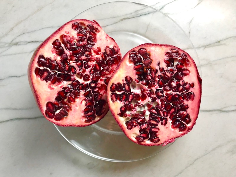Pomegranate cut in half on plate for Quinoa & Kale Salad with Roasted Chickpeas, Pomegranate, Feta, red pepper, and Creamy Lemon Dressing. #glutenfree #lunch #dinner #healthyrecipes #healthyfood #salads #quinoa #kale