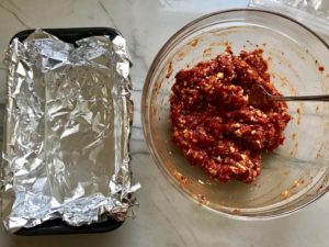 5-Ingredient Chipotle Meatloaf mixed in bowl next to foil lined pan. This recipe adds a spicy mexican flare with Chipotle Peppers in Adobo Sauce and Cheddar Cheese. It's incredibly easy, incredibly moist, and incredibly delicious! A family dinner favorite! #meatloaf #mexican #easydinner #familydinner #dinner #easyrecipes #beef