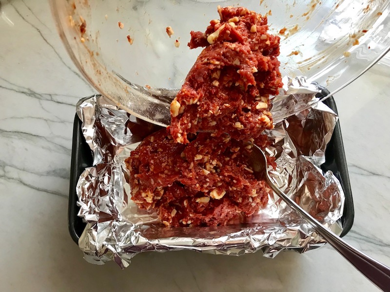 Adding meatloaf mixture to aluminum lined loaf pan for Mexican meatloaf.