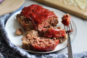 5-Ingredient Chipotle Meatloaf sliced on white plate. This recipe adds a spicy mexican flare with Chipotle Peppers in Adobo Sauce and Cheddar Cheese. It's incredibly easy, incredibly moist, and incredibly delicious! A family dinner favorite! #meatloaf #mexican #easydinner #familydinner #dinner #easyrecipes #beef