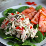 Curry Chicken Salad on spinach with tomato slices. It has so many fantastic flavors and textures!  The chicken breast is simply roasted and mixed with a creamy sweet and savory curry dressing.  Red pepper gives you a fresh crunch, scallion gives a savory bite, and raisins give a burst of sweet.  #chicken #chickenrecipes #chickensalad #currychicken #mealprep #lunch #healthyrecipes