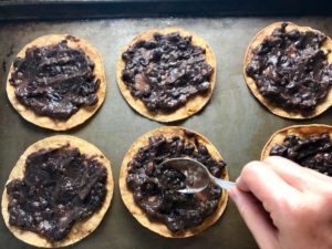 Mashed Black Beans spread on tortillas for Huevos Tostadas! They are similar to Huevos Rancheros but are a pick up and eat with your hands version! They have crispy corn tortillas topped with creamy mashed black beans, a salty fried egg, smoky tomato sauce, cheese, and scallions! #huevosrancheros #eggs #brunch #mexicanrecipes #vegetarian #meatlessrecipes #glutenfree
