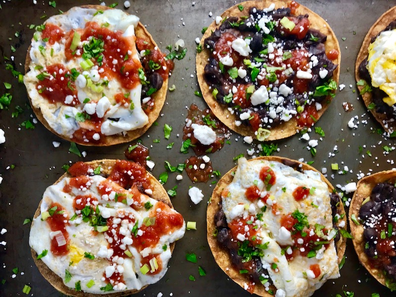 Huevos Tostadas are utterly delicious! They are similar to Huevos Rancheros but are a pick up and eat with your hands version! They have crispy corn tortillas topped with creamy mashed black beans, a salty fried egg, smoky tomato sauce, cheese, and scallions! #huevosrancheros #eggs #brunch #mexicanrecipes #vegetarian #meatlessrecipes