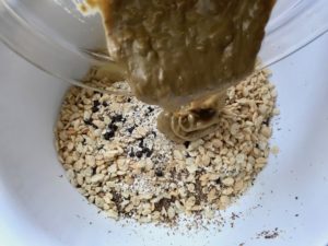 Pouring honey & Sun Butter mixture into dry ingredients for No Bake Energy Bites. These Easy Nut-Free, No-Bake Energy Bites with Chocolate Chips are magnificent! They are sweet, chewy, crunchy, & healthy. Only minutes to make & no Baking! Breakfast, snack, or dessert. #energybars #granolabars #snackrecipes #healthyfood #healthyrecipes #healthysnacks #healthybreakfast #healthydessert