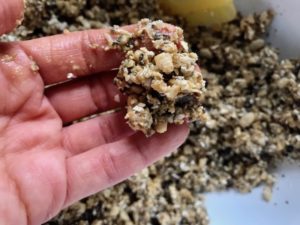 Hand holding mixed ingredients for No Bake Energy Bites. These Easy Nut-Free, No-Bake Energy Bites with Chocolate Chips are magnificent! They are sweet, chewy, crunchy, & healthy. Only minutes to make & no Baking! Breakfast, snack, or dessert. #energybars #granolabars #snackrecipes #healthyfood #healthyrecipes #healthysnacks #healthybreakfast #healthydessert