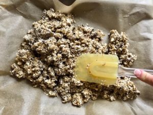 Adding mixed ingredients to parchment lined pan for No Bake Energy Bites. These Easy Nut-Free, No-Bake Energy Bites with Chocolate Chips are magnificent! They are sweet, chewy, crunchy, & healthy. Only minutes to make & no Baking! Breakfast, snack, or dessert. #energybars #granolabars #snackrecipes #healthyfood #healthyrecipes #healthysnacks #healthybreakfast #healthydessert