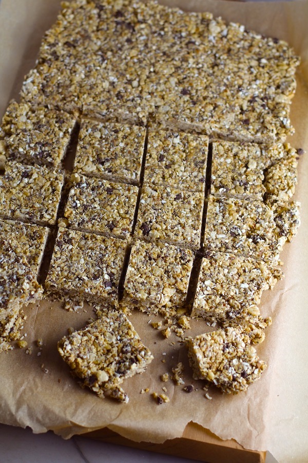 No Bake Energy Bites on parchment and cut into squares. These Easy Nut-Free, No-Bake Energy Bites with Chocolate Chips are magnificent! They are sweet, chewy, crunchy, & healthy. Only minutes to make & no Baking! Breakfast, snack, or dessert. #energybars #granolabars #snackrecipes #healthyfood #healthyrecipes #healthysnacks #healthybreakfast #healthydessert
