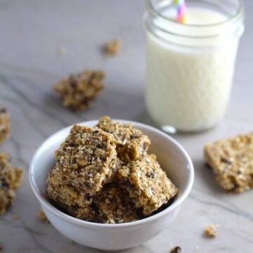 No Bake Energy Bites in a bowl with pieces on counter and glass of milk. These Easy Nut-Free, No-Bake Energy Bites with Chocolate Chips are magnificent! They are sweet, chewy, crunchy, & healthy. Only minutes to make & no Baking! Breakfast, snack, or dessert. #energybars #granolabars #snackrecipes #healthyfood #healthyrecipes #healthysnacks #healthybreakfast #healthydessert