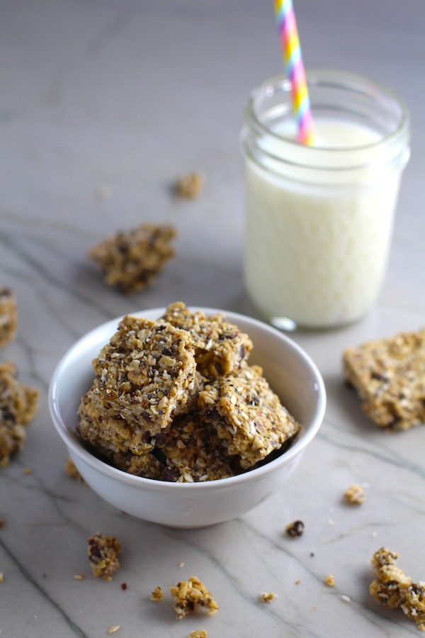 No Bake Energy Bites in a bowl with pieces on counter and glass of milk. These Easy Nut-Free, No-Bake Energy Bites with Chocolate Chips are magnificent! They are sweet, chewy, crunchy, & healthy. Only minutes to make & no Baking! Breakfast, snack, or dessert. #energybars #granolabars #snackrecipes #healthyfood #healthyrecipes #healthysnacks #healthybreakfast #healthydessert