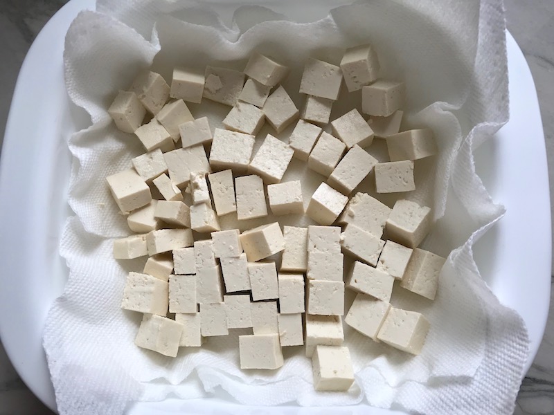 Extra Firm Tofu pieces on paper towel for Roasted Tofu Croutons. These are seasoned and toasted for the perfect addition to any salad, pasta, rice, or soup! They get a roasted, almost nutty flavor with a salty and smoky seasoned crust with a chewy bite. Super easy to make, low carb and great source of protein! #croutons #salad #tofu #tofurecipes #vegetarian #plantbased #paleo