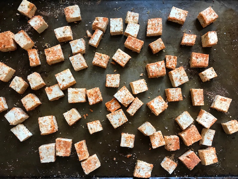 Seasoned tofu pieces on pan for Roasted Tofu Croutons. These are seasoned and toasted for the perfect addition to any salad, pasta, rice, or soup! They get a roasted, almost nutty flavor with a salty and smoky seasoned crust with a chewy bite. Super easy to make, low carb and great source of protein! #croutons #salad #tofu #tofurecipes #vegetarian #plantbased #paleo