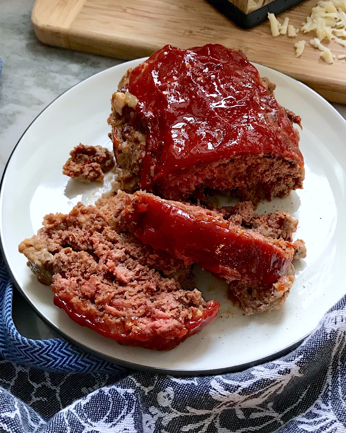Taco Meatloaf sliced on white plate. This recipe adds a spicy mexican flare with Chipotle Peppers in Adobo Sauce and Cheddar Cheese. It's incredibly easy, incredibly moist, and incredibly delicious! A family dinner favorite!