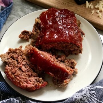 Taco Meatloaf sliced on white plate. This recipe adds a spicy mexican flare with Chipotle Peppers in Adobo Sauce and Cheddar Cheese.  It's incredibly easy, incredibly moist, and incredibly delicious!  A family dinner favorite!