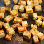 Savory Baked Tofu Bites on pan. These are seasoned and toasted for the perfect addition to any salad, pasta, rice, or soup!   They get a roasted, almost nutty flavor with a salty and smoky seasoned crust with a chewy bite.  Super easy to make, low carb and great source of protein!  #croutons #salad #tofu #tofurecipes #vegetarian #plantbased #paleo
