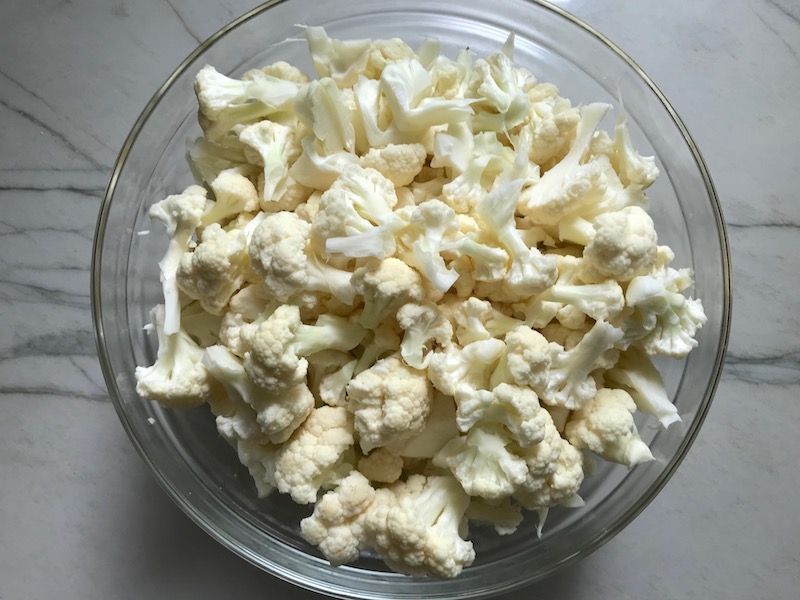 Cauliflower florets in bowl for Cauliflower Cordon Bleu Bake recipe. It layers in nutty and salty Gruyere Cheese, with a creamy Vegetable broth based sauce with garlic and parsley. Then the ham and cauliflower are folded into all of this goodness and it's baked in the oven until it all becomes one knock-your-socks-off dish! #cauliflower #lowcarb #glutenfree #casserole #onepot #familydinner #mealprep #easydinner #dinner #healthydinner #healthyfood #healthyrecipes