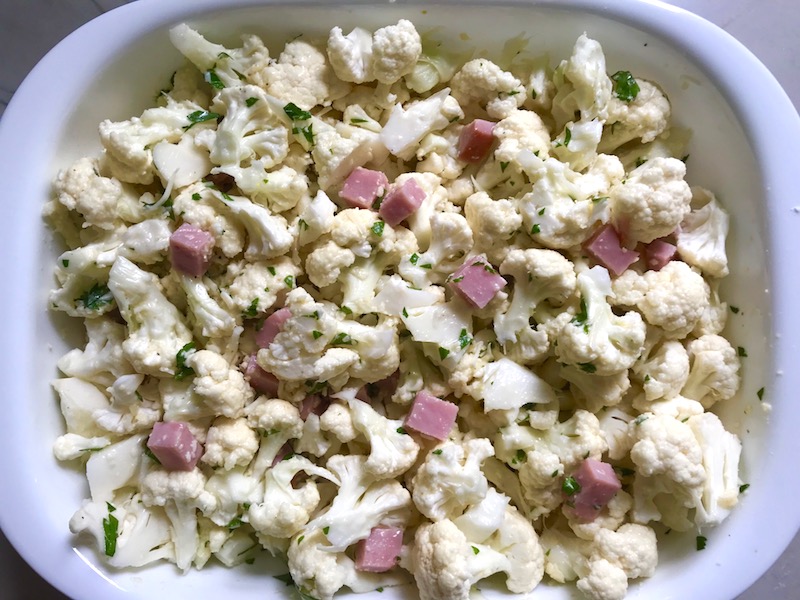 Raw Cauliflower Cordon Bleu Bake in dish. It layers in nutty and salty Gruyere Cheese, with a creamy Vegetable broth based sauce with garlic and parsley. Then the ham and cauliflower are folded into all of this goodness and it's baked in the oven until it all becomes one knock-your-socks-off dish! #cauliflower #lowcarb #glutenfree #casserole #onepot #familydinner #mealprep #easydinner #dinner #healthydinner #healthyfood #healthyrecipes