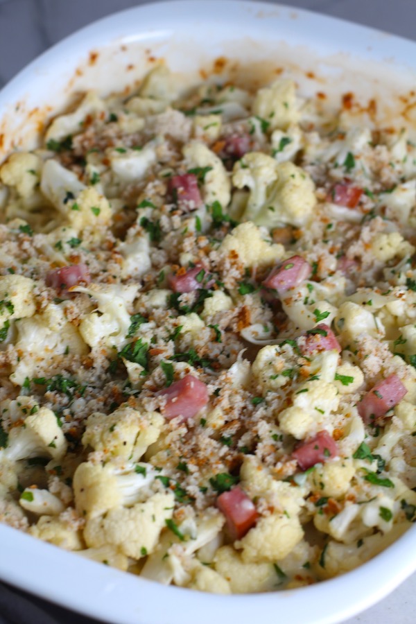 Close up of Cauliflower Cordon Bleu Bake with parsley and breadcrumb topping. It layers in nutty and salty Gruyere Cheese, with a creamy Vegetable broth based sauce with garlic and parsley.  Then the ham and cauliflower are folded into all of this goodness and it's baked in the oven until it all becomes one knock-your-socks-off dish! #cauliflower #lowcarb #glutenfree #casserole #onepot #familydinner #mealprep #easydinner #dinner #healthydinner #healthyfood #healthyrecipes