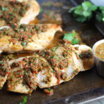 Chicken Chimichurri Rojo on a pan. It is broiled or grilled Chicken topped with a cool, fresh, tangy, and incredibly full-flavored!  The Rojo comes from the addition of red pepper.  All of the ingredients simply get blended in a food processor so it could not be easier!  #chicken #chickenrecipes #chimichurri #easychicken #easydinners #dinner