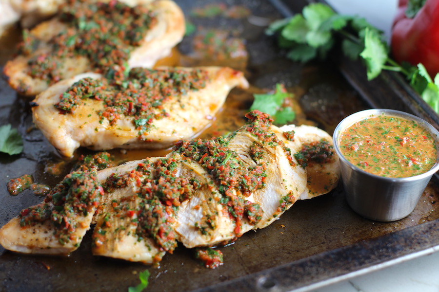 Chicken Chimichurri Rojo on a pan. It is roasted Chicken topped with a cool, fresh, tangy, and incredibly full-flavored! The Rojo comes from the addition of red pepper. All of the ingredients simply get blended in a food processor so it could not be easier! #chicken #chickenrecipes #chimichurri #easychicken #easydinners #dinner