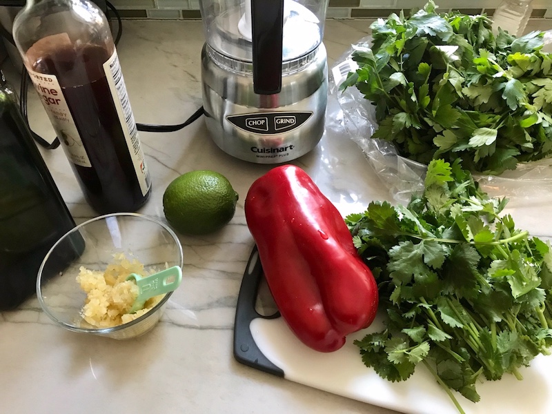 Ingredients on counter for the Chicken Chimichurri Rojo. It is broiled or grilled Chicken topped with a cool, fresh, tangy, and incredibly full-flavored! The Rojo comes from the addition of red pepper. All of the ingredients simply get blended in a food processor so it could not be easier! #chicken #chickenrecipes #chimichurri #easychicken #easydinners #dinner