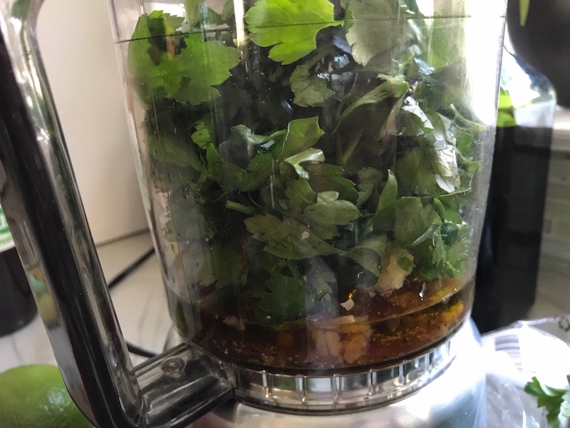 Parsley in food processor for the Chicken Chimichurri Rojo. It is broiled or grilled Chicken topped with a cool, fresh, tangy, and incredibly full-flavored! The Rojo comes from the addition of red pepper. All of the ingredients simply get blended in a food processor so it could not be easier! #chicken #chickenrecipes #chimichurri #easychicken #easydinners #dinner