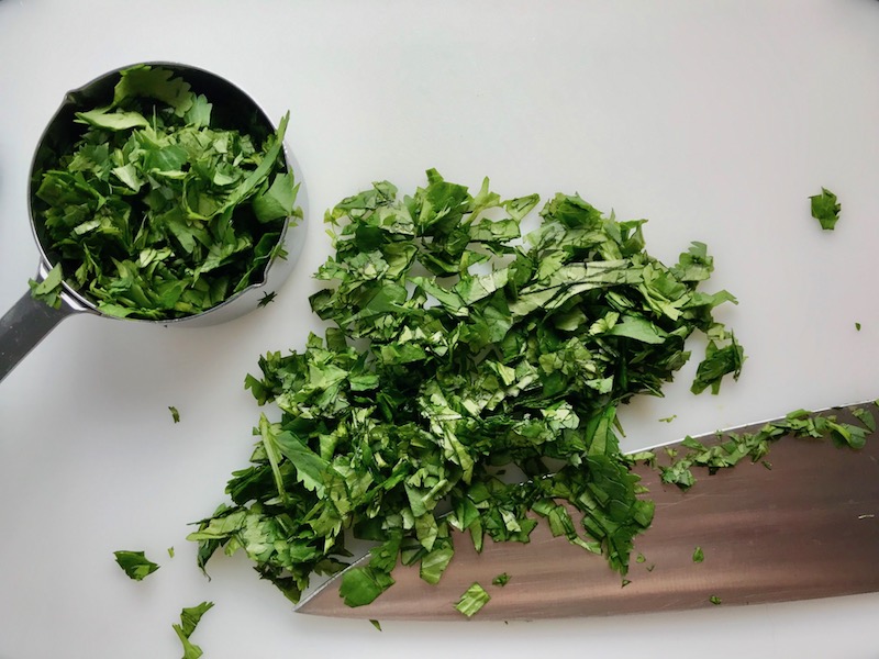 Chopped cilantro on cutting board for Cilantro Lime Quinoa. It's fluffy, nutty, citrusy, salty, and the perfect accompaniment for any protein or vegetable! With just a few simple ingredients, you can make this fantastic healthier alternative to rice. #quinoa #quinoarecipes #sides #healthyfood
