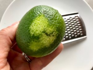 Zesting lime for Cilantro Lime Quinoa. It's fluffy, nutty, citrusy, salty, and the perfect accompaniment for any protein or vegetable!  With just a few simple ingredients, you can make this fantastic healthier alternative to rice. #quinoa #quinoarecipes #sides #healthyfood