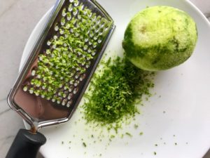 Lime zested with zester and zest next to it for Easy Tzatziki recipe.