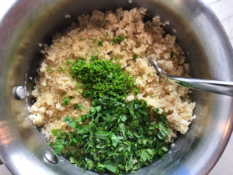 Chopped cilantro and lime zest on quinoa in pot for Cilantro Lime Quinoa. It's fluffy, nutty, citrusy, salty, and the perfect accompaniment for any protein or vegetable! With just a few simple ingredients, you can make this fantastic healthier alternative to rice. #quinoa #quinoarecipes #sides #healthyfood
