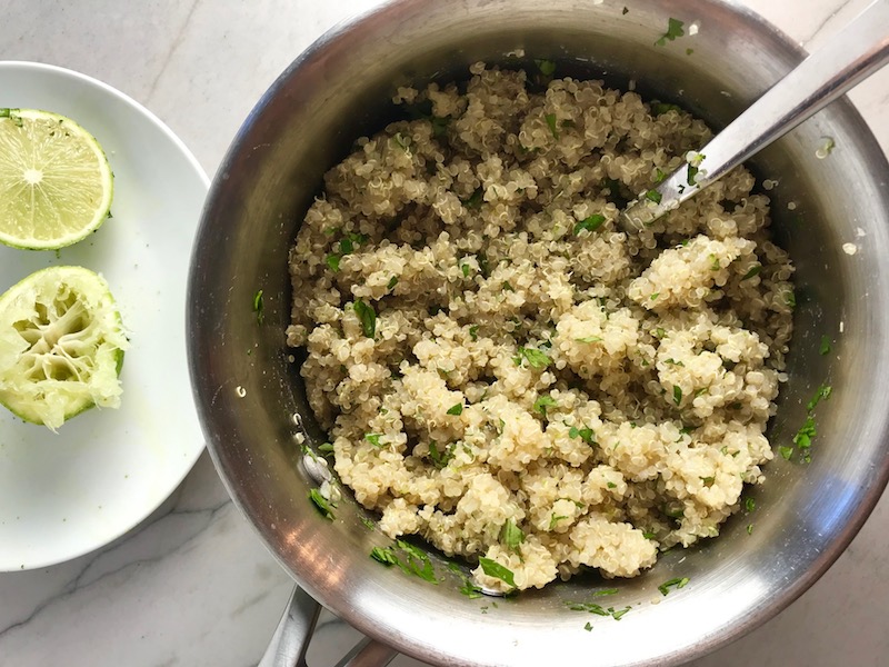 Cilantro Lime Quinoa in a bowl with spoon with lime and cilantro on counter. It's fluffy, nutty, citrusy, salty, and the perfect accompaniment for any protein or vegetable! With just a few simple ingredients, you can make this fantastic healthier alternative to rice. #quinoa #quinoarecipes #sides #healthyfood