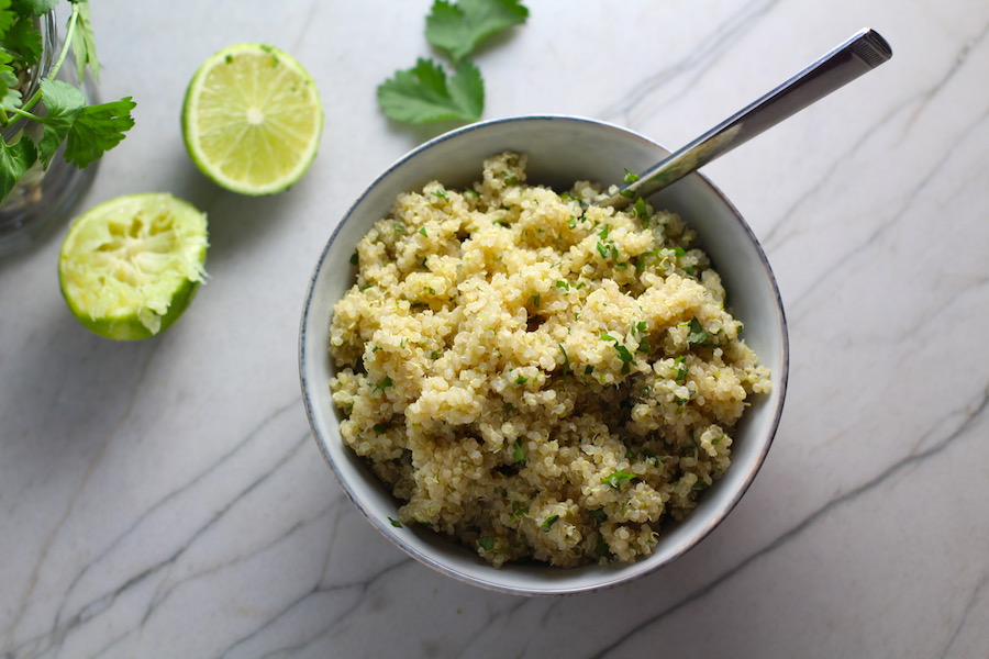 Cilantro Lime Quinoa in a bowl with spoon with lime and cilantro on counter. It's fluffy, nutty, citrusy, salty, and the perfect accompaniment for any protein or vegetable! With just a few simple ingredients, you can make this fantastic healthier alternative to rice. #quinoa #quinoarecipes #sides #healthyfood