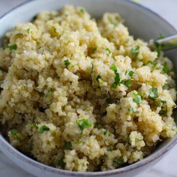 Cilantro Lime Quinoa in a bowl with spoon. It's fluffy, nutty, citrusy, salty, and the perfect accompaniment for any protein or vegetable!  With just a few simple ingredients, you can make this fantastic healthier alternative to rice. #quinoa #quinoarecipes #sides #healthyfood
