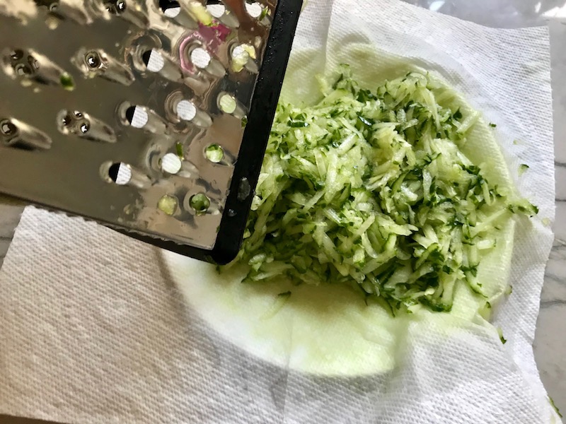 Cucumber shredded with grater over paper towel for Garlic and Lime Shrimp with Tzatziki Sauce. The Shrimp is simply sauteed with minced garlic, olive oil, and lemon for big bold flavors. The Tzatziki Sauce is bright and cool with creamy yogurt with fresh cucumber, lime, garlic, and scallion. #shrimp #easydinner #dinner #seafoodrecipes #shrimprecipes