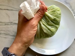 Hand holding cucumber wrapped in paper towel for Garlic and Lime Shrimp with Tzatziki Sauce. The Shrimp is simply sauteed with minced garlic, olive oil, and lemon for big bold flavors. The Tzatziki Sauce is bright and cool with creamy yogurt with fresh cucumber, lime, garlic, and scallion. #shrimp #easydinner #dinner #seafoodrecipes #shrimprecipes