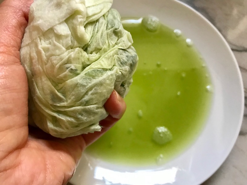 Hand squeezing cucumber wrapped in paper towel for Garlic and Lime Grilled Greek Shrimp with Tzatziki Sauce. The Shrimp is simply sauteed with minced garlic, olive oil, and lemon for big bold flavors. The Tzatziki Sauce is bright and cool with creamy yogurt with fresh cucumber, lime, garlic, and scallion. #shrimp #easydinner #dinner #seafoodrecipes #shrimprecipes