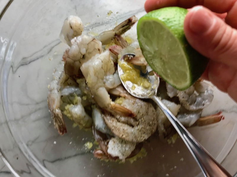 Squeeze lime over raw shrimp for Garlic Lime Grilled Greek Shrimp with Tzatziki Sauce. The Shrimp is simply sauteed with minced garlic, olive oil, and lemon for big bold flavors. The Tzatziki Sauce is bright and cool with creamy yogurt with fresh cucumber, lime, garlic, and scallion. #shrimp #easydinner #dinner #seafoodrecipes #shrimprecipes