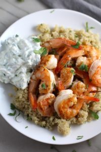 Garlic and Lime Shrimp with Tzatziki Sauce over Quinoa on plate. The Shrimp is simply sauteed with minced garlic, olive oil, and lime for big bold flavors. The Tzatziki Sauce is bright and cool with creamy yogurt with fresh cucumber, lime, garlic, and scallion. #shrimp #easydinner #dinner #seafoodrecipes #shrimprecipes