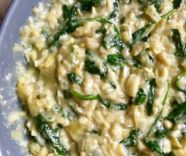 Spinach artichoke stuffing in pan for Artichoke Spinach Stuffed Zucchini Recipe. Each fantastic bite gives you creamy artichoke, nutty cheesy Parmesan, spinach, and zucchini. Prepare entirely ahead, then bake 20 minutes and enjoy! #vegetarian #zucchini #stuffedzuchini #spinach #artichoke #springrecipes #healthyfood #healthydinner #healthyrecipes #glutenfree