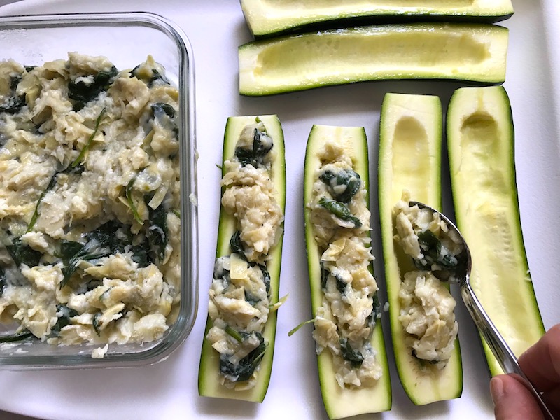 Stuffing zucchini halves for Artichoke Spinach Stuffed Zucchini Recipe. Each fantastic bite gives you creamy artichoke, nutty cheesy Parmesan, spinach, and zucchini. Prepare entirely ahead, then bake 20 minutes and enjoy! #vegetarian #zucchini #stuffedzuchini #spinach #artichoke #springrecipes #healthyfood #healthydinner #healthyrecipes #glutenfree