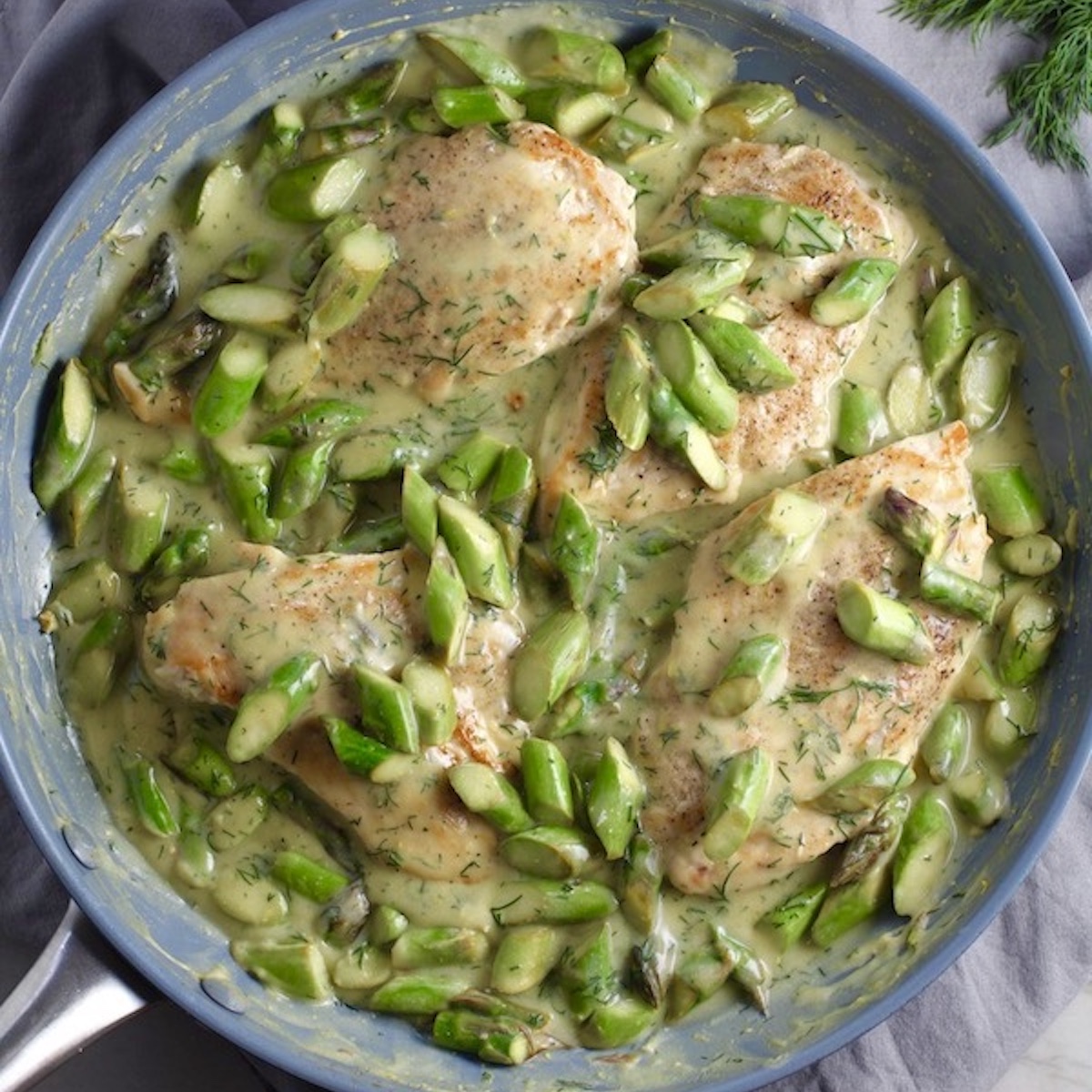 Cooked Lemon Dill Sauce Chicken and Asparagus in pan on stove. It has chicken in a light and creamy sauce flavored with garlic, lemon and fresh dill. It's loaded with fresh asparagus. #springrecipes #dinner #easydinner #healthydinner #lemon #asparagus #chicken #glutenfree #easyrecipes