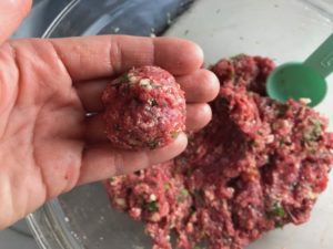 Raw meatball in hand over meat bowl for Meatballs in Cauliflower Dill Cream Sauce. #meatballs #swedishmeatballs #familydinner #easydinner #dinner #healthydinner