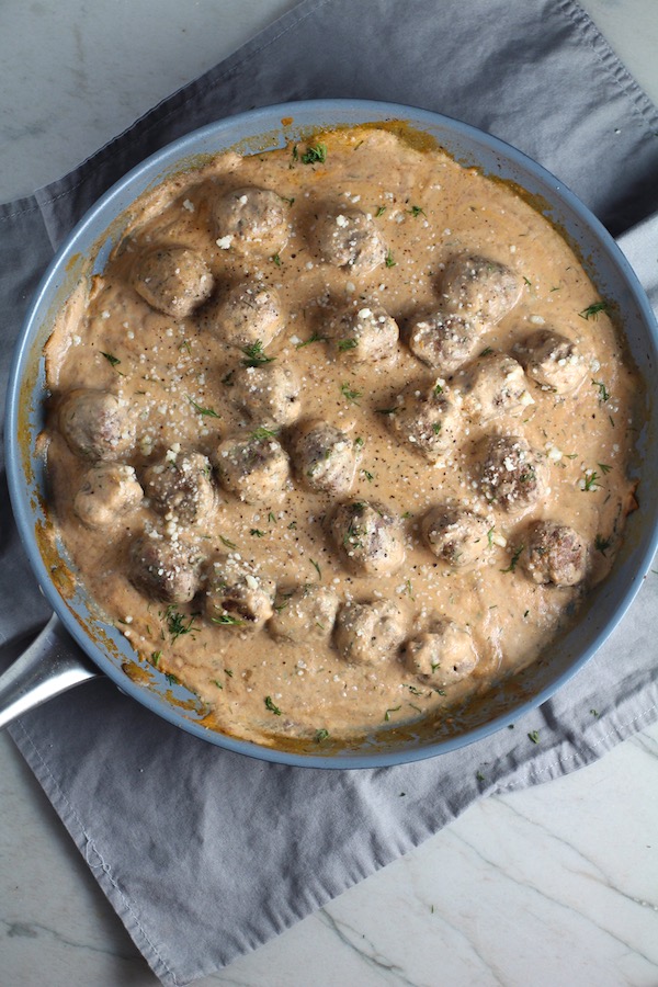 Meatballs in Cauliflower Dill Cream Sauce in a skillet. The Meatballs are swimming in a beautiful creamy cauliflower sauce flavored with garlic, fresh dill, cream cheese, and a touch of tomato paste. #meatballs #swedishmeatballs #familydinner #easydinner #dinner #healthydinner